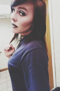 Close-up portrait of young woman standing against wall