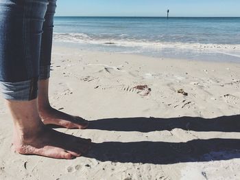 Low section of person on beach against clear sky