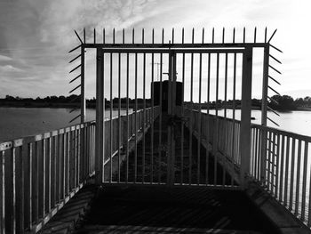 Metal gate by sea against sky