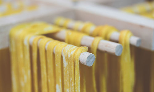 Close-up of yellow pasta hanging on stick at kitchen