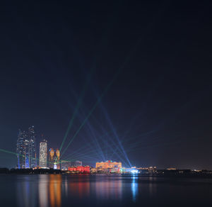 Illuminated city by river at night