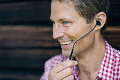 Happy man using hands-free device outside log cabin