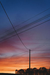 Silhouette electricity pylon against romantic sky at sunset