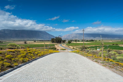 Road amidst field against sky