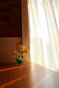 Flower vase on table by window at home