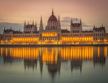 Illuminated hungarian parliament building by river at dusk