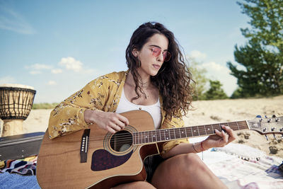 Young woman playing guitar at beach