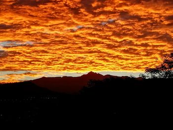 Scenic view of silhouette mountains against orange sky