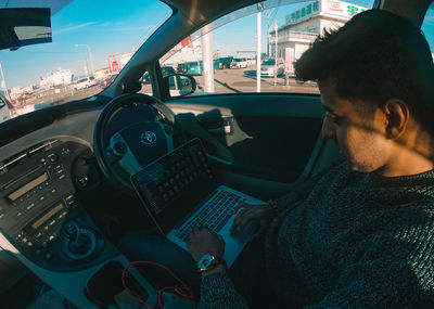 Midsection of man using mobile phone while sitting in car