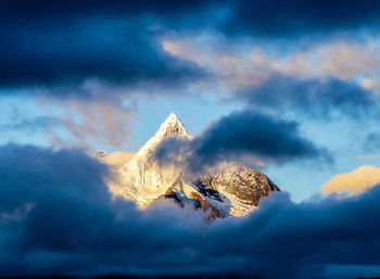 Scenic view of snow covered mountains against cloudy sky