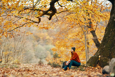 Full length of man sitting on road during autumn