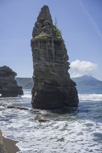 Rock formation on beach against sky