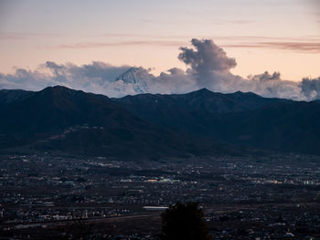 Aerial view of townscape and mountains against sky at sunset
