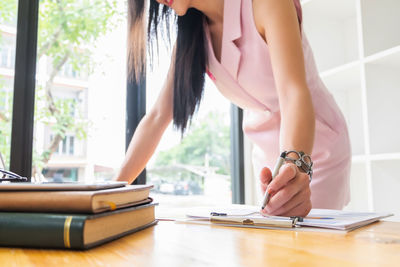 Midsection of woman reading book at home