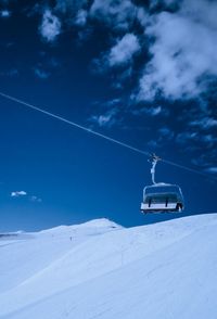 Ski lift on snowcapped mountain against sky