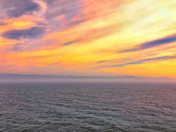 Scenic view of sea against dramatic sky during sunset