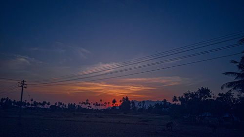 Silhouette electricity pylon against sky during sunset