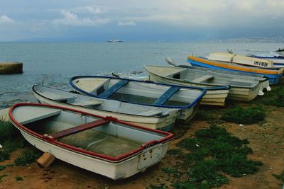 Boats moored on sea shore against sky