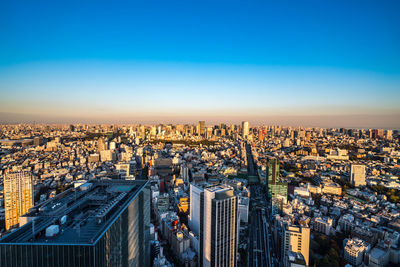 High angle view of city buildings against blue sky