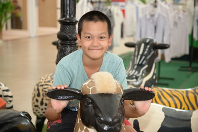 Portrait of smiling boy sitting on toy in shopping mall