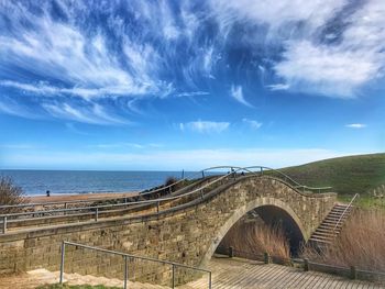 Arch bridge over sea against sky