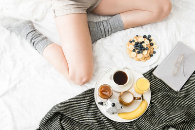 High angle view of woman holding coffee cup on bed