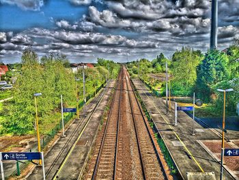 Panoramic view of railroad tracks amidst field against sky