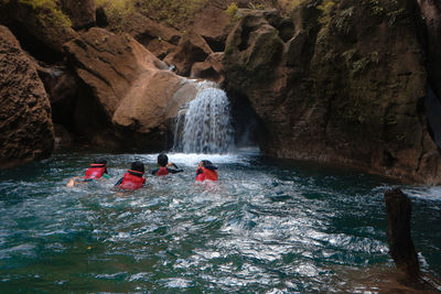 People on rock formation in sea