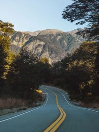 Country road amidst trees against sky