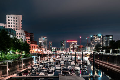 River by illuminated buildings in city at night