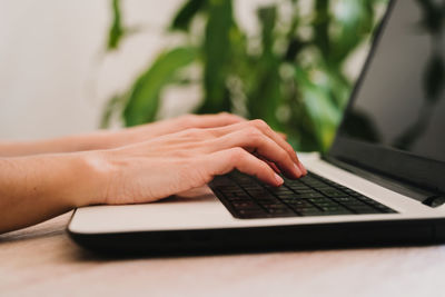 Cropped hands using laptop at table