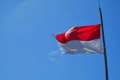 Low angle view of flag against clear blue sky