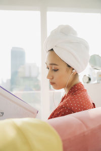 Portrait of young woman looking through window