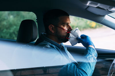 Driver adjusting his face mask in the car. driving with covid-19.