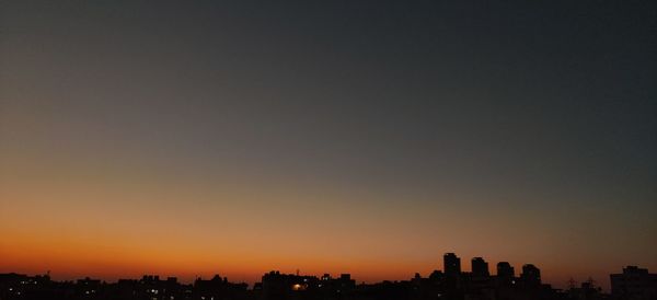 Silhouette buildings against sky during sunset