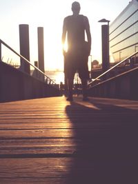 Silhouette of woman walking on footbridge