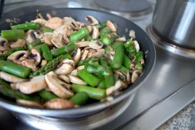 High angle view of mushrooms and asparagus in pan on stove 