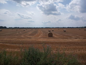 Hay bales on field against sky