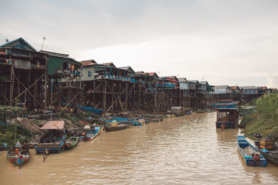 Boats moored on river against sky in city