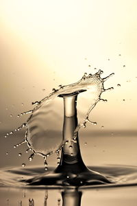 Close-up of drop falling on water against white background