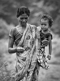 Poor mother holding son while standing on land