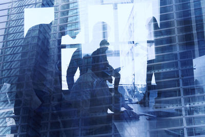 Digital composite image of people working on glass building