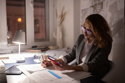 Female architect reading client notes and correcting draft