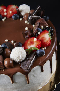 Cake decorated with strawberry and chocolate on dark background