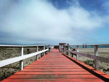 Pier on sea against cloudy sky