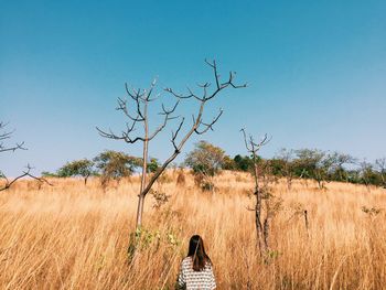 Rear view of woman on field against clear blue sky