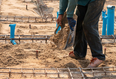 Workers fill the ground with sand to level and prepare for pouring mortar.