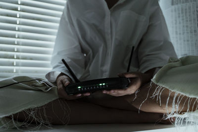 Midsection of man using mobile phone on bed at home