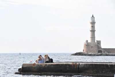 Lighthouse by sea against sky