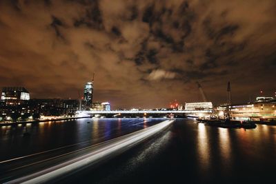 Illuminated cityscape against cloudy sky